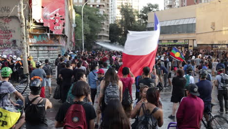 Man-carries-a-large-Chilean-flag-through-the-crowd-of-protesters-in-the-streets-of-Santiago