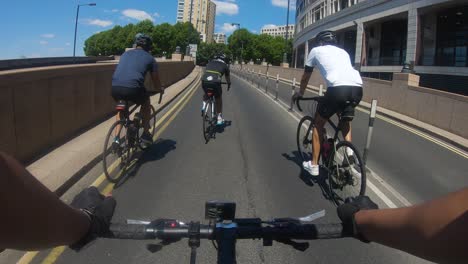 POV-Of-Cyclists-Riding-Up-Westferry-Road-In-Canary-Wharf-With-Bus-Going-Past