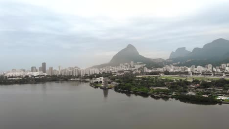 Aerial-pan-around-the-city-lake-with-a-partly-constructed-floating-Christmas-tree-on-the-shore-of-the-city-lake-in-Rio-de-Janeiro-on-a-hazy-early-morning-with-the-wider-cityscape-in-the-background