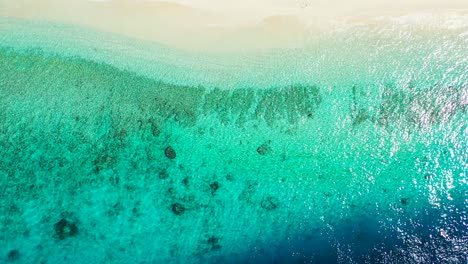 Bunte-Meeresstruktur-Mit-Blauem-Wasser,-Das-Sonnenlicht-Reflektiert,-Und-Türkisfarbener-Lagune,-Die-Den-Weißen-Sand-Eines-Exotischen-Strandes-In-Der-Karibik-Umspült