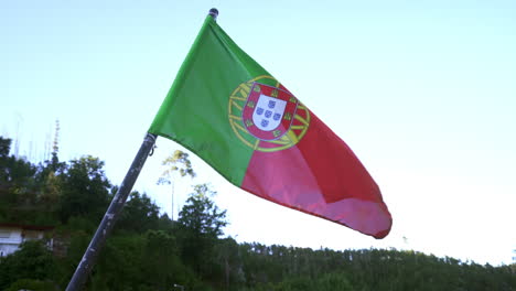 Die-Flagge-Portugals-Weht-In-Der-Luft,-üppige-Bäume-Im-Hintergrund-–-Nach-Unten-Geneigter-Schwenk