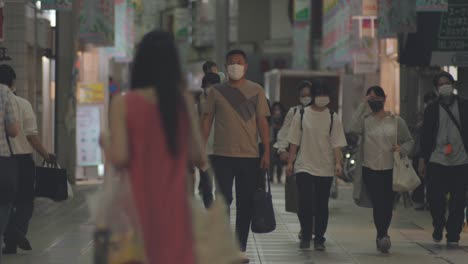 Japoneses-Con-Máscaras-Protectoras-Caminando-Por-La-Calle-De-Kamata-Por-La-Noche-Durante-El-Brote-De-Coronavirus-En-Tokio,-Japón