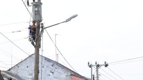Blurred-and-noise-clip,-Electrician-lineman-repairman-worker-at-climbing-work-on-electric-post-power-pole,-Pekalongan