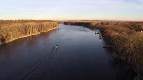 Aerial-shot,-following-a-boat-along-the-Mississippi-river-in-Minnesota,-just-before-sunset