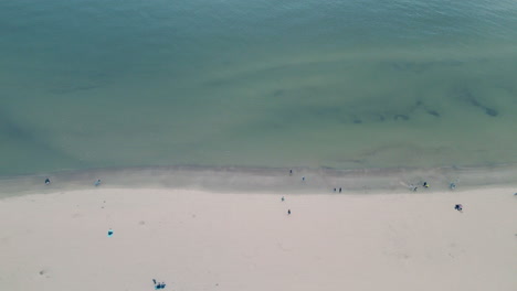 Down-view-from-drone---unrecognizable-people-walking-along-the-white-sand-beach-near-the-baltic-sea-in-Sopot-city-in-northern-Poland