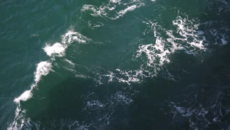 Turquoise-green-water-surface-viewn-from-a-ferry-with-waves-in-it