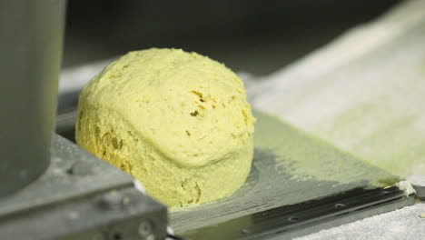 Yellow-Dough-In-A-Bread-Divider-And-Moulder-Machine-In-A-Bakery---close-up