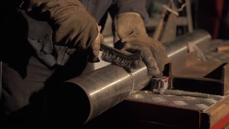 Welder-cleaning-weld-flux-using-wire-brush-on-stainless-steel-pipe