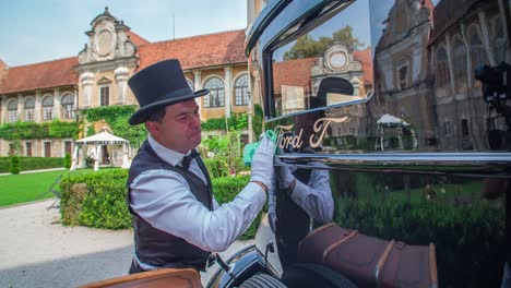 Man-with-top-hat-and-formal-vest-cleans-a-vintage-Ford-Model-T-car-window