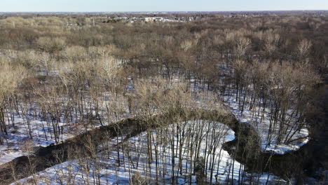 Rising-drone-footage-of-winding-stream-in-winter-in-Michigan