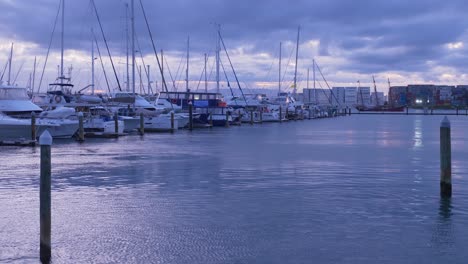 Sailboats-Moored-At-The-Pier-In-Tauranga,-New-Zealand-As-Viewed-From-The-Bridge-On-A-Moody,-Overcast-Day---wide-tilt-up-shot