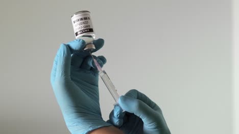 Close-up-shot-of-nurse's-hands-wearing-surgical-gloves,-holding-syringe-sucking-out-vaccine-for-covid-19