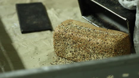 Hands-Of-A-Baker-Remove-Freshly-Baked-Loaf-Bread-With-Sesame-Seeds-From-A-Baking-Pan