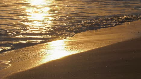 Ocean-waves-on-golden-sandy-beach-at-sunrise,-mediterranean-coast-of-Spain