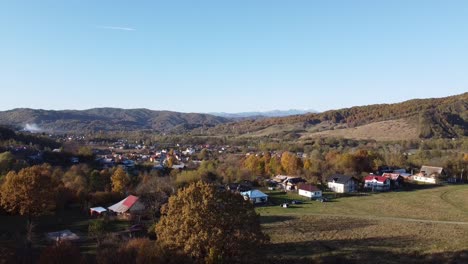 Aerial-above-view-of-epic-colorful-autumn-forest-and-a-rural-vilage-on-a-sunny-day