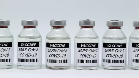 Row-Of-Covid-Vaccine-Glass-Vials-Isolated-In-White-Background---Sars-Cov-2-Vaccination-Concept---slider-right,-studio-shot