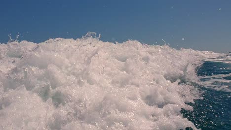 Low-angle-pov-of-water-splash-on-sea-surface-behind-speedboat