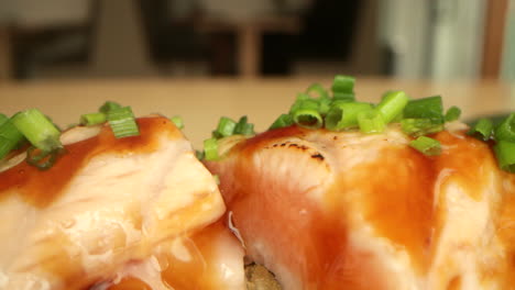 Salmon-Sushi-Rolls-Garnished-With-Fresh-Onion-Chives---macro,-slow-panning-shot