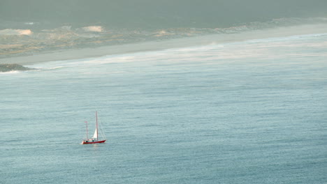 Barco-Navegando-En-El-Mar-Azul-Cerca-De-La-Playa-Norte-En-Nazare,-Portugal-Al-Amanecer