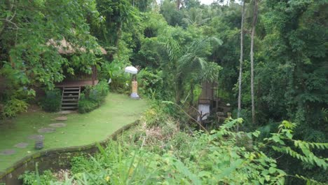 Idyllic-Bali-Island-Tropical-Scenery,-Aerial-View-of-Gazebo-and-Creek-in-a-Green-Rainforest-Landscape,-Dolly-Left-Drone-Shot
