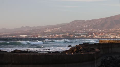 Beautiful-view-of-the-waves-crashing-at-the-shoreline-with-a-city-in-the-background,-Tenerife