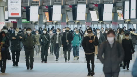 Lokale-Passagiere-Mit-Maske-Und-Winterkleidung-Gehen-Während-Der-Pandemie-In-Tokio,-Japan,-Am-Bahnhof-Shinagawa-Spazieren