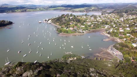 A-lowering-aerial-drone-shot-of-Mangonui-town,-harbour-and-boats-on-the-Doubtless-Bay-in-Northland,-New-Zealand,-Aotearoa