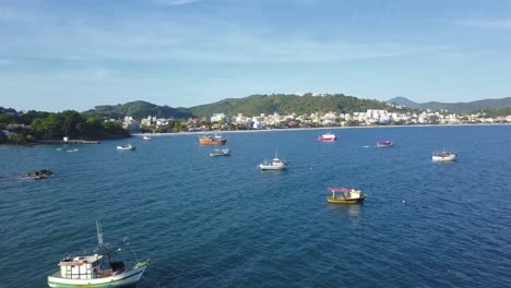 Toma-Aérea-Sobrevolando-Barcos-De-Pesca-Que-Trabajan-En-El-Mar-Cerca-De-La-Playa-De-Bombinhas,-Brasil
