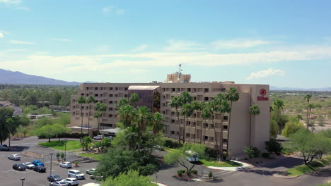Aerial-view-of-Hilton-Hotel-in-front-of-a-mountain-with-a-clear-blue-sky,-in-Tucson-Arizona,-pan-down