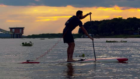 A-man-gets-up-on-a-paddle-board-on-the-Rio-Paraguay-during-an-amazing-sunset