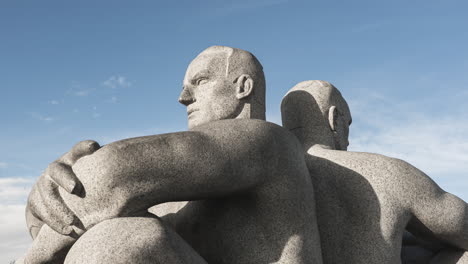 Granite-Sculpture-Of-Two-Men-Sitting-Back-to-Back-With-Crossed-Arms-At-Vigeland-Installation-In-Frognerparken,-Oslo,-Norway