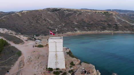 Stone-tower-with-the-Order-of-Malta-knights-flag-above-a-bay,aerial