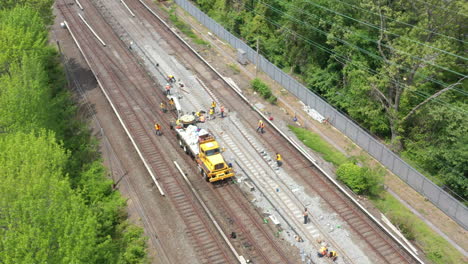 an-aerial-view-over-workers-repairing-train-tracks-on-a-sunny-morning
