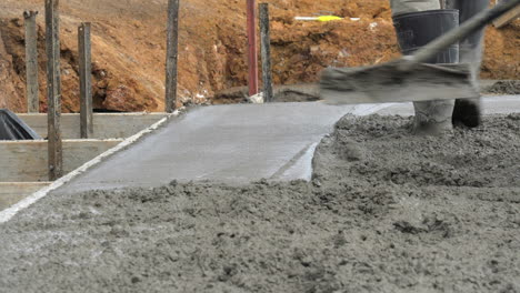 Concreter-Smoothing-Newly-Laid-Cement-Slab-With-Long-Trowel,-SLOW-MOTION