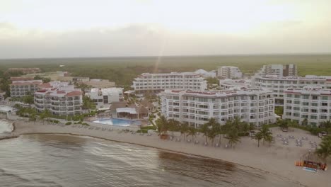 AERIAL---Sunset-over-a-hotel-and-its-swimming-pools-in-Cancun,-Mexico,-forward