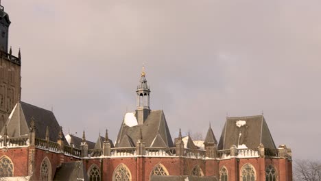 Slow-pan-and-reveal-of-the-Walburgiskerk-cathedral-tower-in-winter-snow-landscape-at-sunset