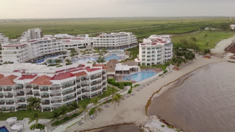 AERIAL---Hotels,-swimming-pools-and-small-bay-in-Cancun,-Mexico,-circle-shot