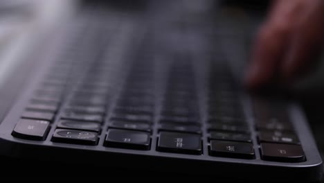Hand-typing-on-a-black-computer-keyboard,-close-up-side-view