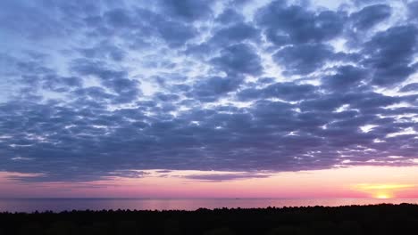 Beautiful-aerial-vibrant-high-contrast-pink-purple-sunset-with-blue-clouds-over-Baltic-sea-at-Liepaja,-distant-ships-in-the-sea,-wide-angle-drone-panorama-shot-moving-right
