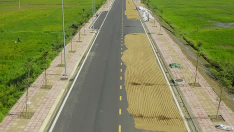 Drone-view-of-the-farmer-is-drying-rice-on-a-road-in-Khanh-Hoa-province,-central-Vietnam