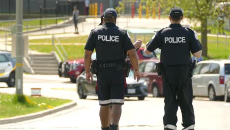 Close-up-view-of-two-police-officers-from-the-back-in-Toronto,-talking-with-a-man-for-information