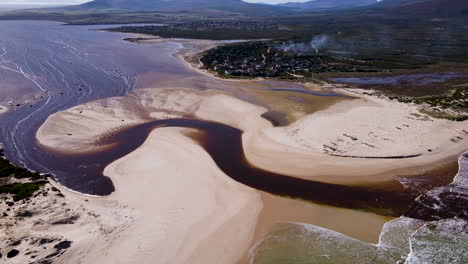 Aerial---Flying-past-Bot-River-mouth,-brown-tannin-rich-water-flows-into-ocean,-Middlevlei,-South-Africa