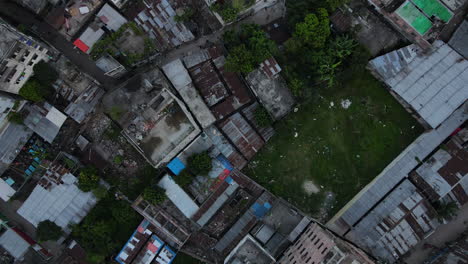 Top-down-aerial-slum-area-with-city-buildings-and-little-green-space---drone-ascending-shot