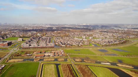Aerial-Pan-Right-View-Across-Barendrecht-Green-Fields-And-Town-With-Rotterdam-Skyline-In-Distance