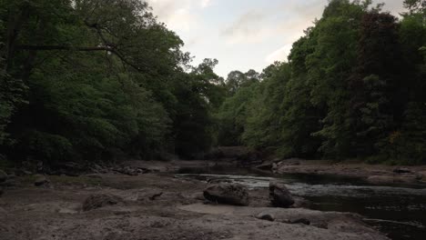 Sanfter-Fluss,-Der-Im-Abendlicht-Durch-Felsen-Und-Bäume-Fließt