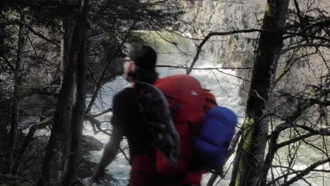 Male-backpacker-trekking-next-to-white-water-river-stream-alone