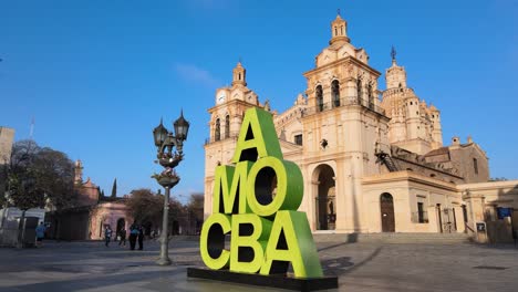 Parallax-of-Amo-Cba-sign-in-front-of-cathedral-in-Córdoba,-Argentina