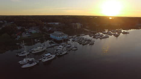 Aerial-of-Lady's-Island-South-Carolina-at-sunset-with-marina,-boats,-bridge,-and-Beaufort-SC-orbiting-clockwise-drone-shot
