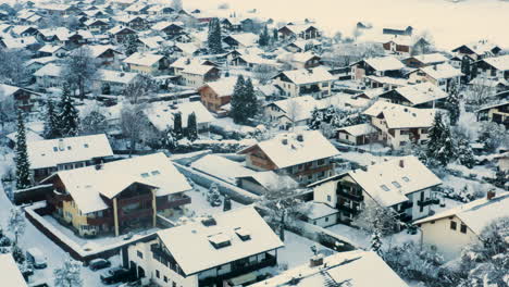 Snowy-houses-in-german-town-of-Garmisch-Partenkirchen,-drone-shot
