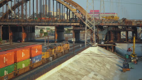 Aufnahme-Eines-Container-Güterzuges,-Der-Langsam-Unter-Der-6th-St-Bridge-In-Der-Innenstadt-Von-Los-Angeles,-USA,-Bei-Sonnenuntergang-Hindurchfährt